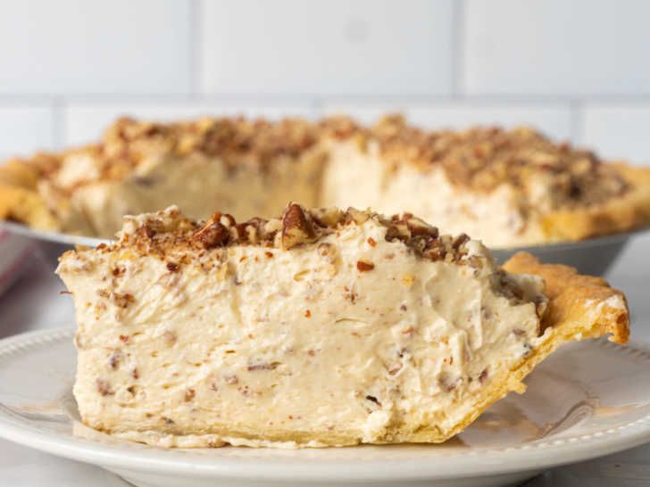 a piece of pie sitting on top of a white plate next to another pie in the background