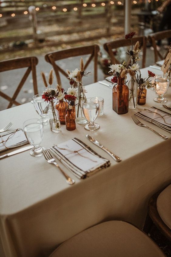 the table is set with silverware and flowers in glass vases on each side