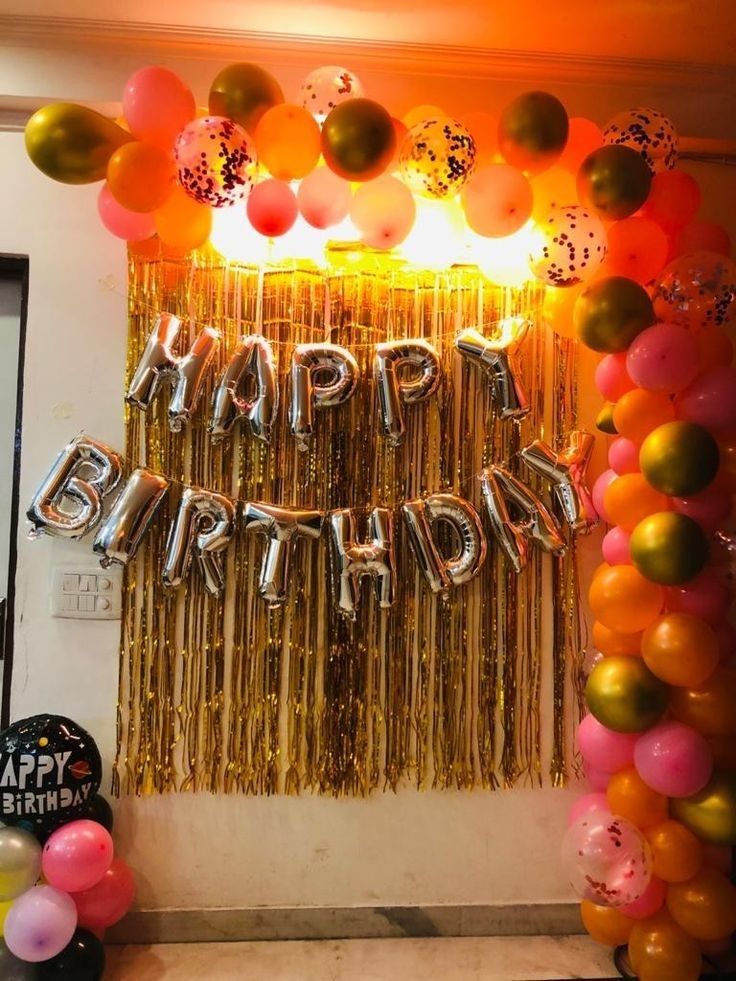 balloons and streamers decorate the entrance to a birthday party with gold, pink, and orange colors