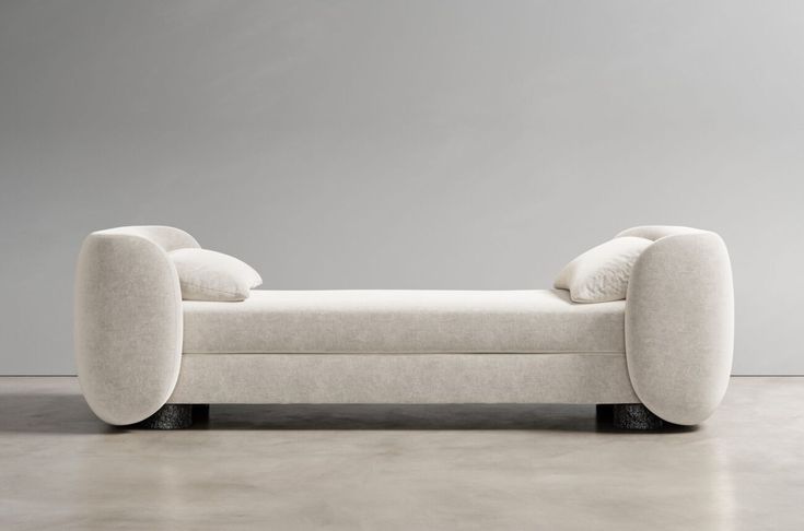 a white couch sitting on top of a floor next to a gray wall in a room