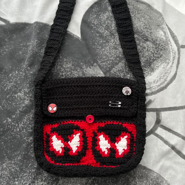 a crocheted black bag with red and white designs