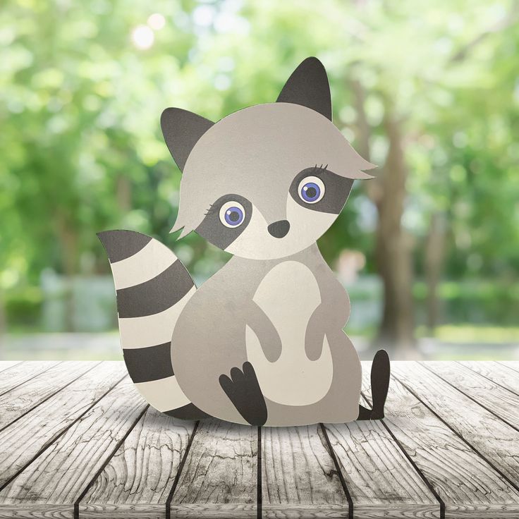 a paper cut out of a raccoon sitting on top of a wooden table