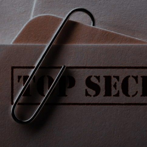 a close up of an envelope with a paperclip on it and the word top secret written in brown