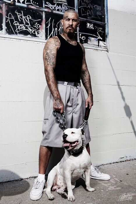 a man standing next to a white and black dog on a leash with graffiti behind him