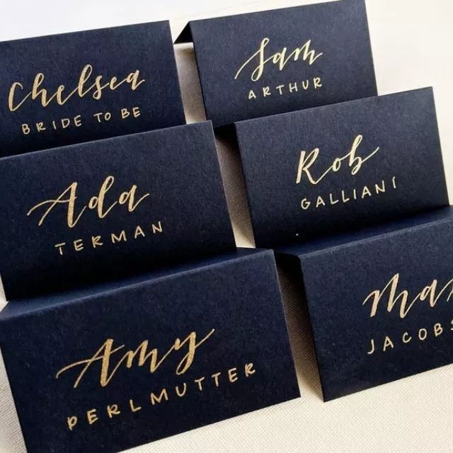 six place cards with gold ink on them