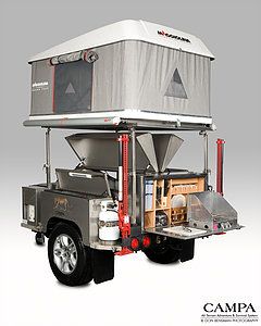 a truck with a tent on the back is parked in front of a gray background