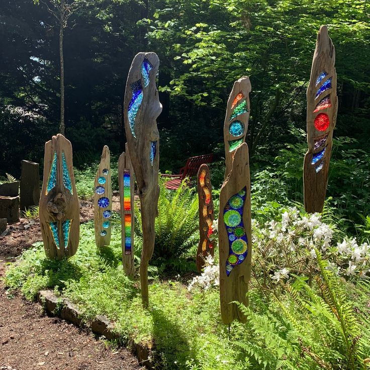 a group of metal sculptures sitting on top of a lush green field next to trees