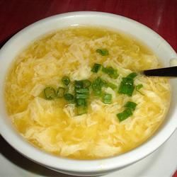 a white bowl filled with soup and green onions