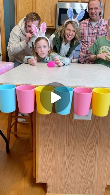 a group of people standing around a kitchen table with cups on it and bunnies hanging from the ceiling