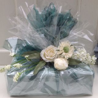 a bouquet of flowers wrapped in plastic sitting on top of a door sill next to a blue box