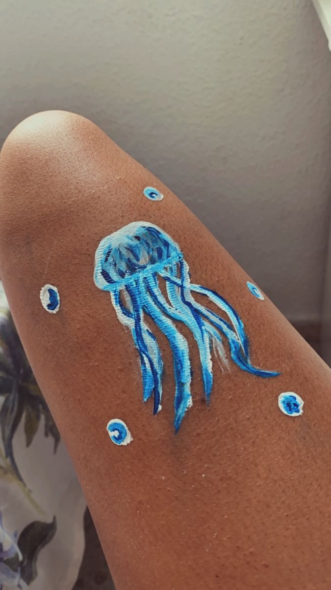 a woman with blue paint on her arm has a jellyfish tattoo on it's arm