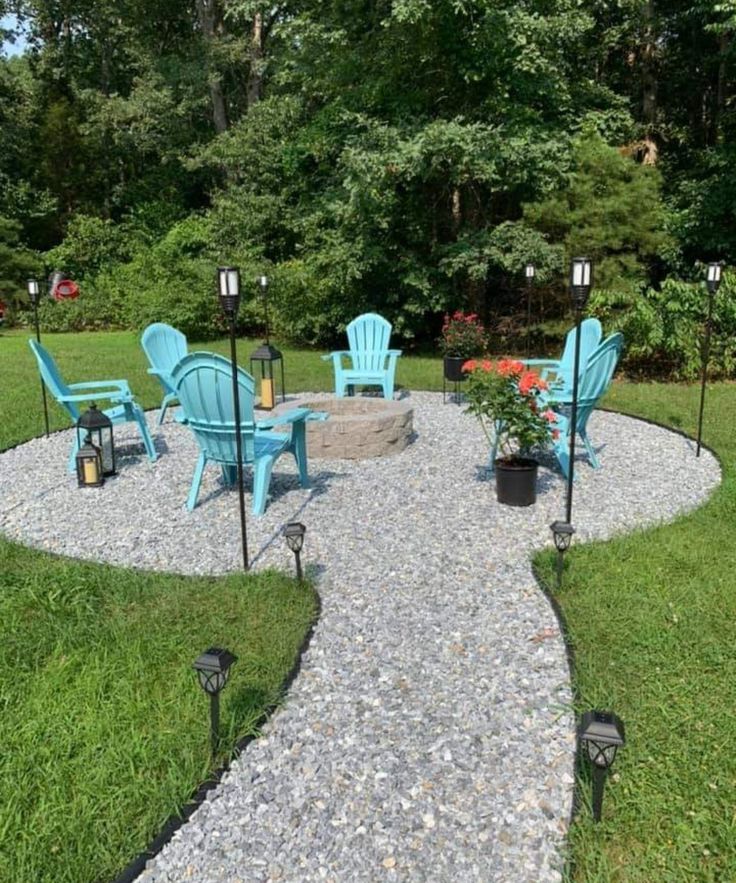 an outdoor patio with chairs and fire pit surrounded by gravel, rocks and plants in the middle