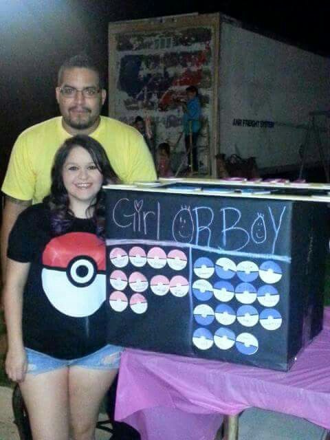 two people standing next to a table with a sign on it that says girl or boy