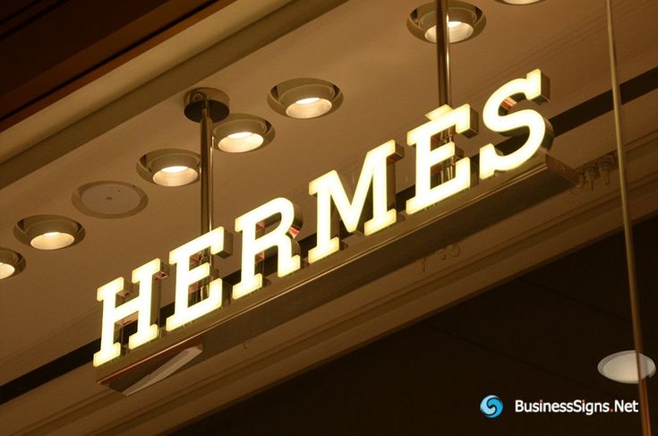 there is a sign that says hermes hanging from the ceiling in front of some lights