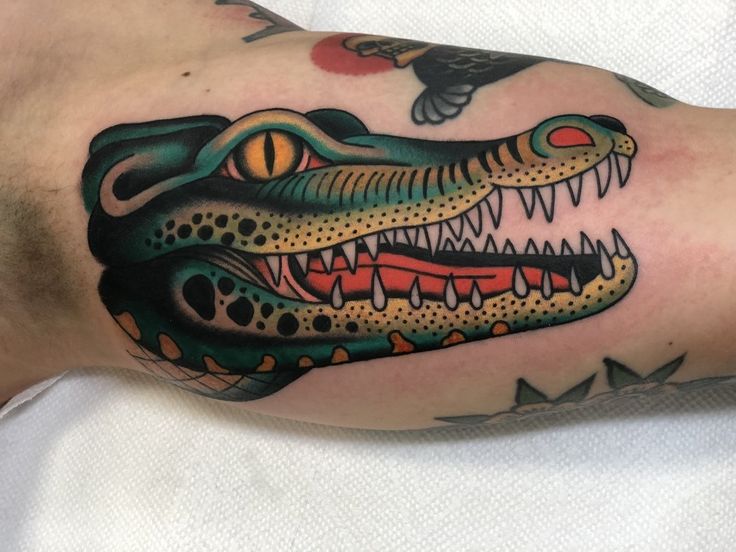 a close up of a person's arm with a tattoo on it and an alligator