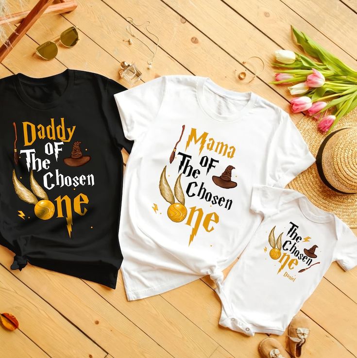 two shirts that say daddy and the chosen one are on top of a wooden floor