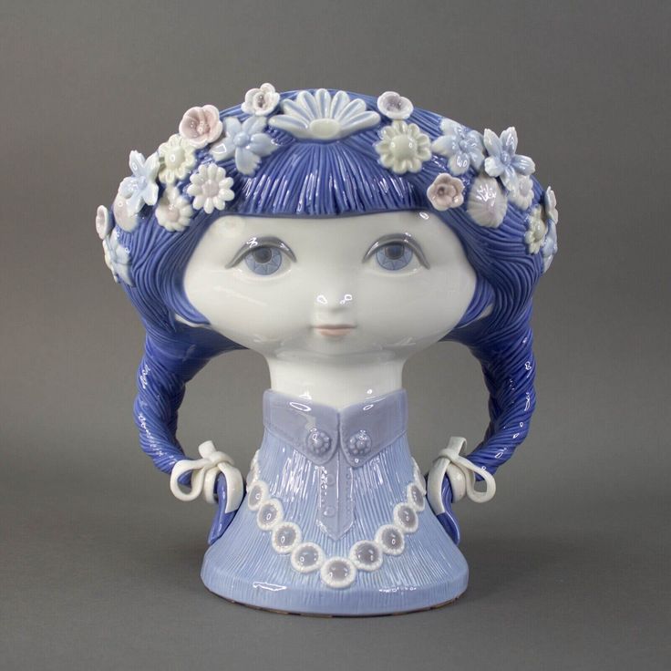 a blue and white porcelain figurine with flowers in her hair