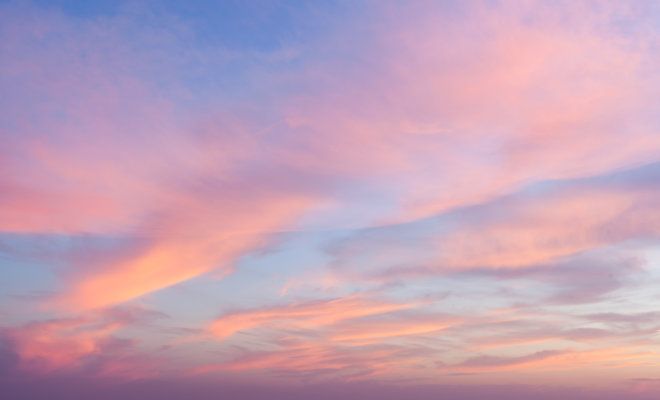 the sky is pink and blue as it sets on an overcast day at the beach