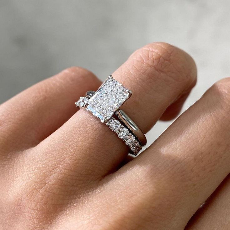 a woman's hand with a diamond ring on her left and an engagement band on her right