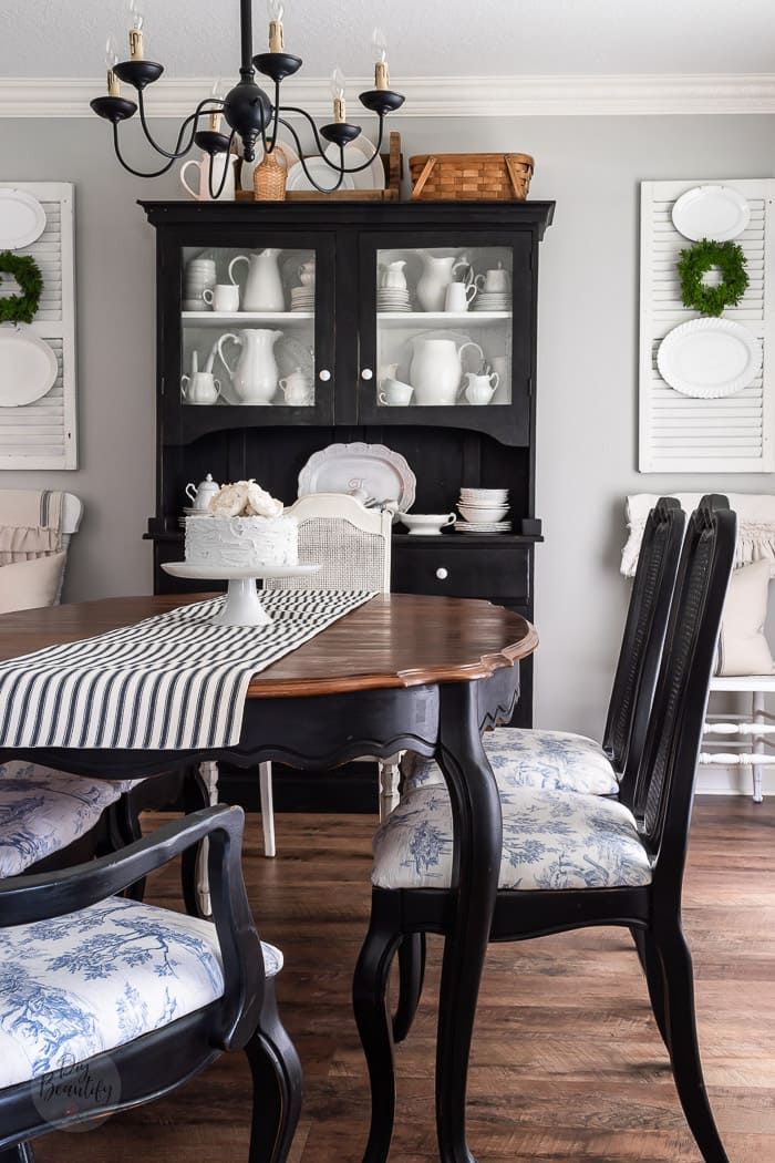 a dining room table with chairs and plates on top of it, in front of a china cabinet