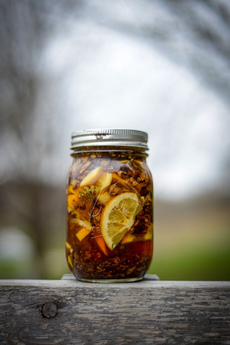 a glass jar filled with food sitting on top of a wooden table next to a tree