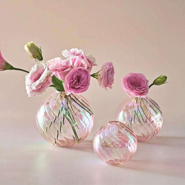 three glass vases with pink flowers in them