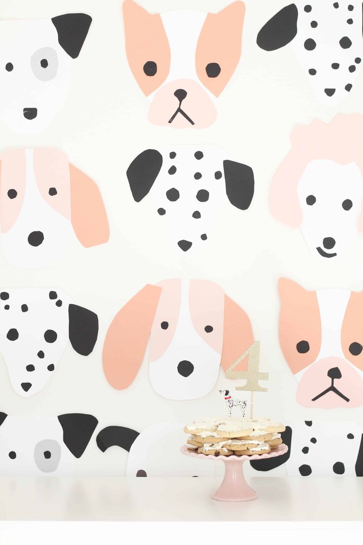 a cake on a plate in front of a wall decorated with dogs and polka dots