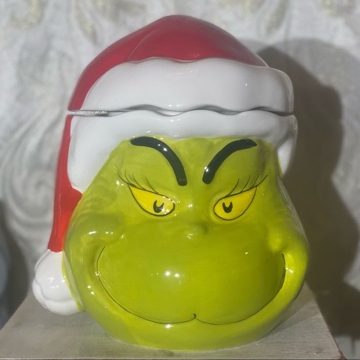 a green grin face mug sitting on top of a table