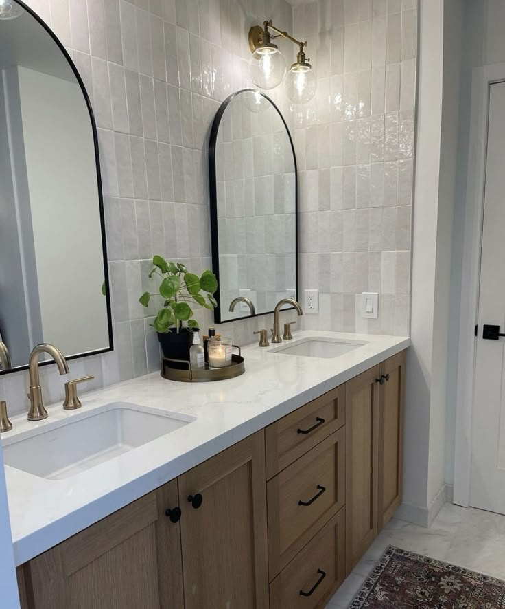 a bathroom with two sinks, mirrors and a rug on the floor in front of it