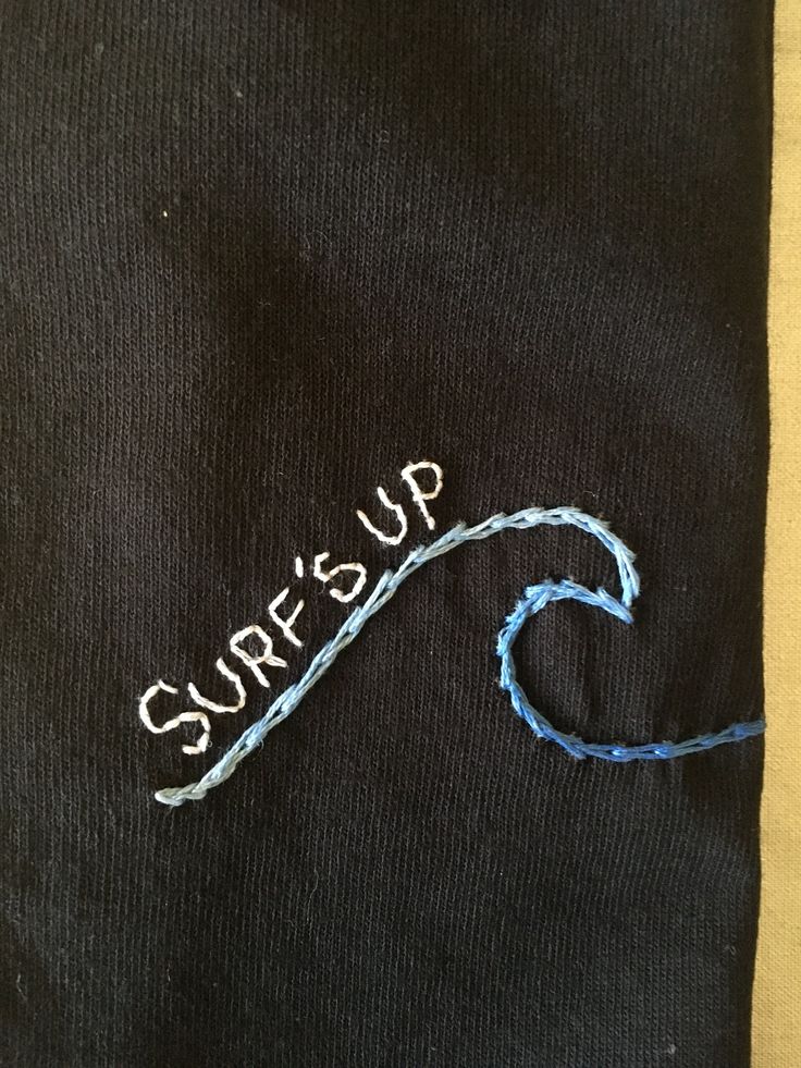 a black shirt with the words surf's up written on it and a blue string