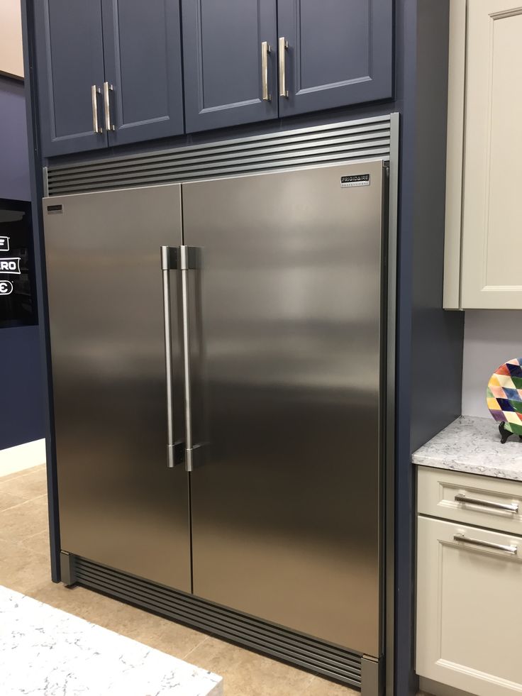 a stainless steel refrigerator in a kitchen with blue cabinets