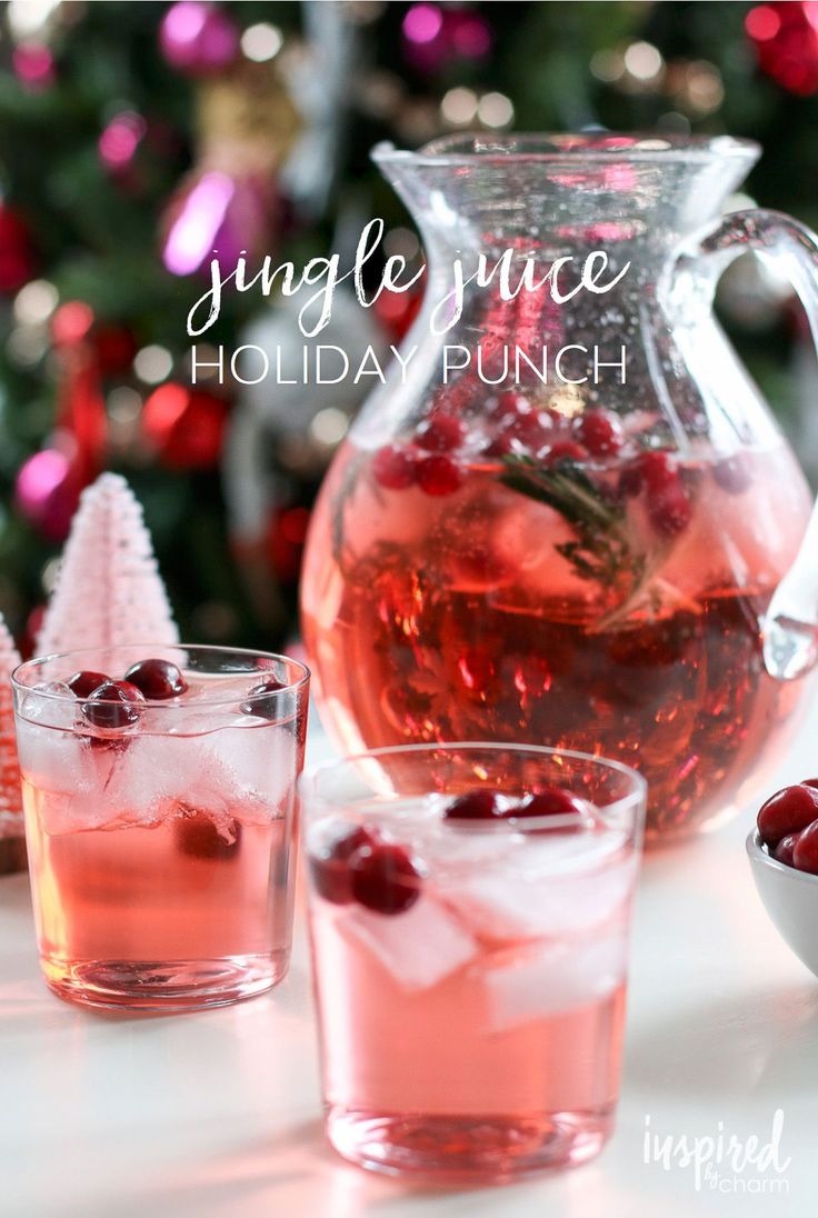 a pitcher and two glasses filled with cranberry punch next to a christmas tree