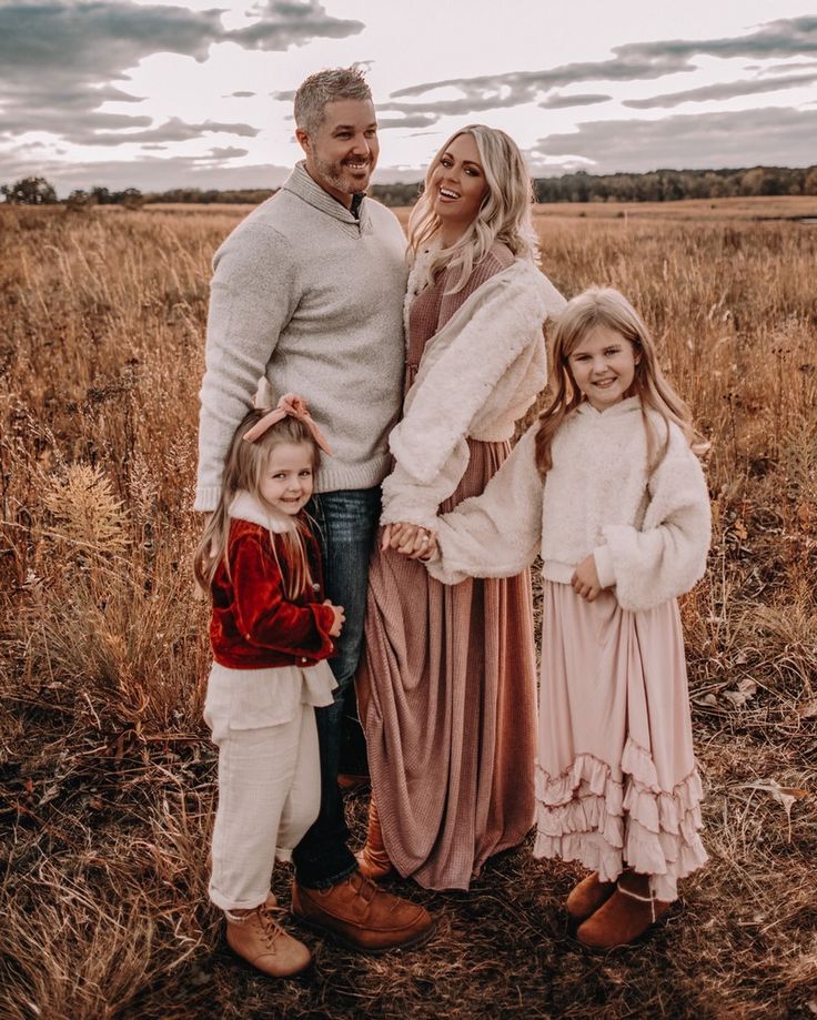 a man, woman and two children posing for a photo in the middle of a field