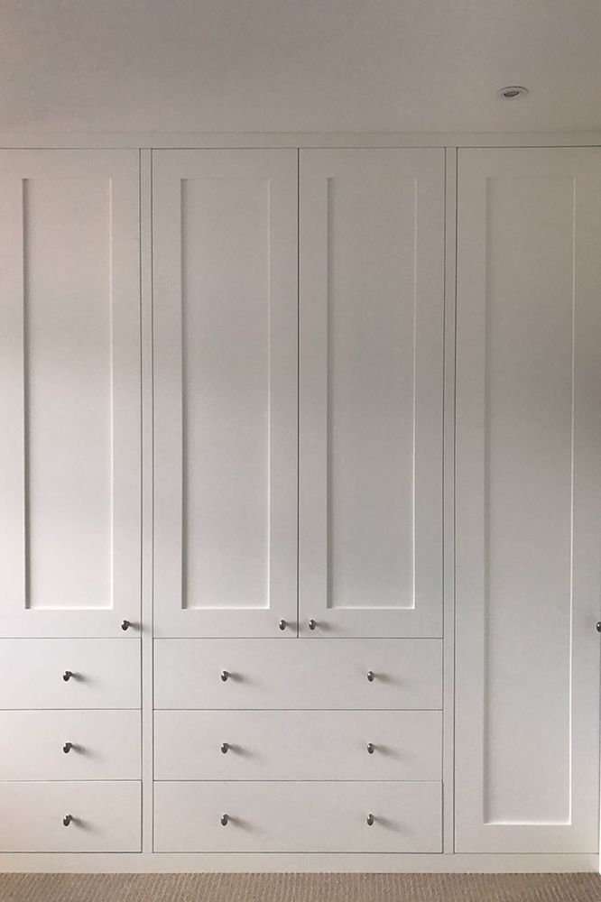 an empty room with white cupboards and carpeted flooring on the side wall