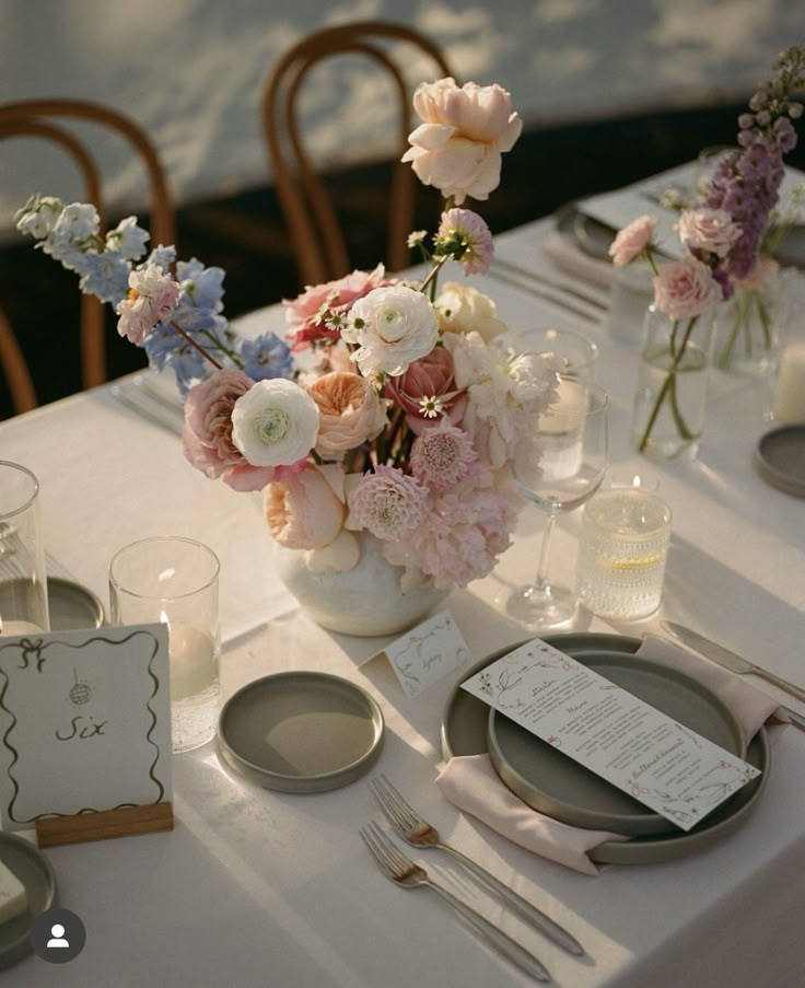 the table is set with flowers in vases and place settings for dinner party guests