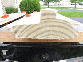 a piece of wood sitting on top of a table in front of a building with trees