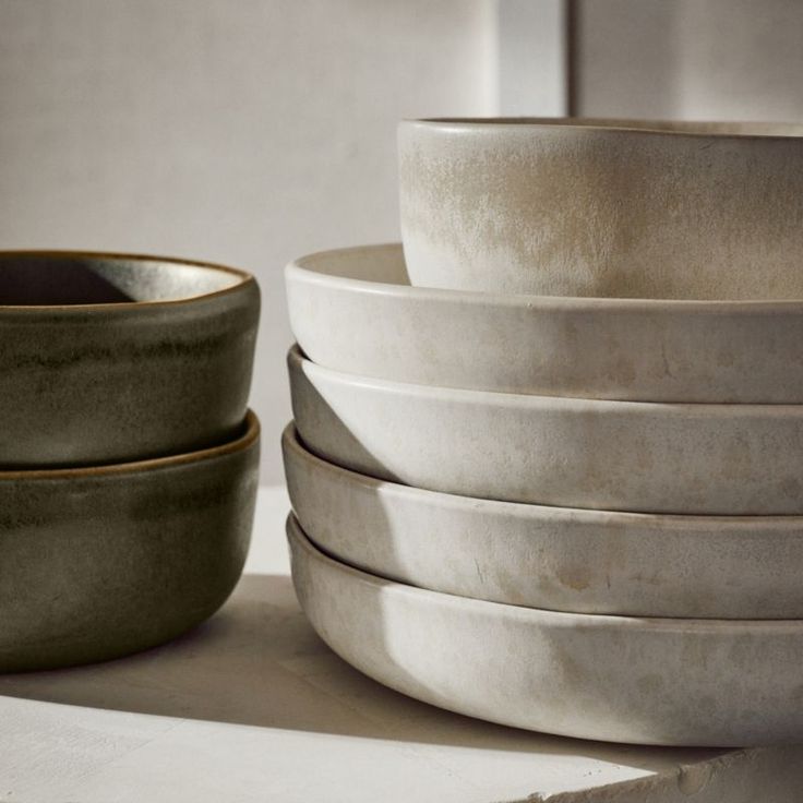 a stack of white bowls sitting next to each other on top of a countertop