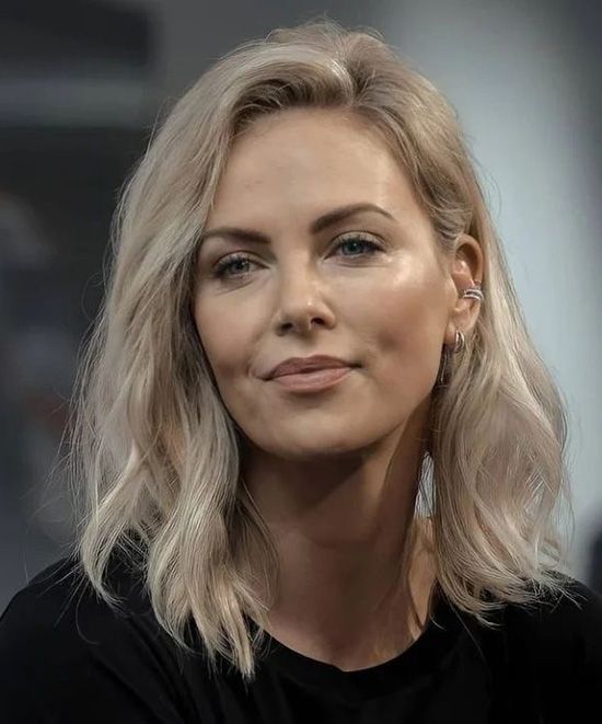 a close up of a person wearing a black shirt and silver earring on her left ear