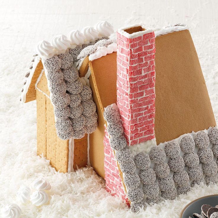 a house made out of cardboard sitting on top of white fluffy carpet next to cookies