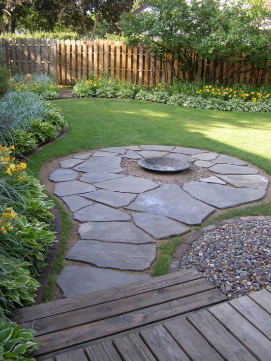 a wooden deck in the middle of a garden with stones and gravel on it's sides