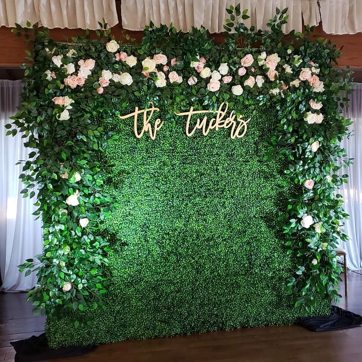 the wedding backdrop is covered with greenery and flowers