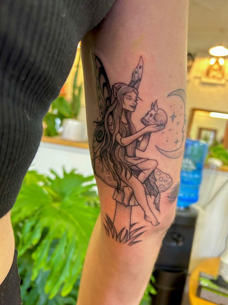 a woman's leg with a tattoo on it and a fairy holding a cat