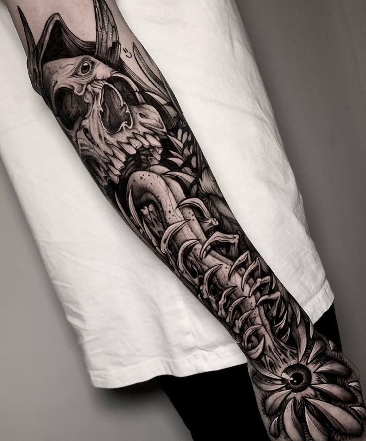 a man's arm with an intricate black and white tattoo design on the forearm