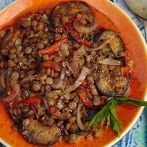 a bowl filled with lentils and mushrooms on top of a blue and white table cloth