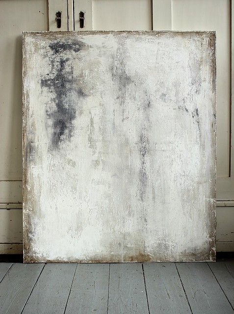 an old, dirty painting is sitting on the floor in front of some cupboards