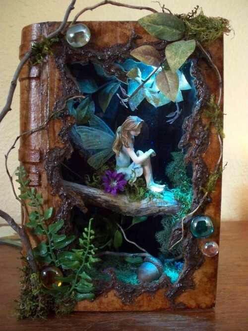 a fairy figurine sitting on top of a wooden box filled with plants and leaves