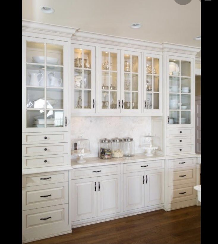 a kitchen with white cabinets and wooden floors