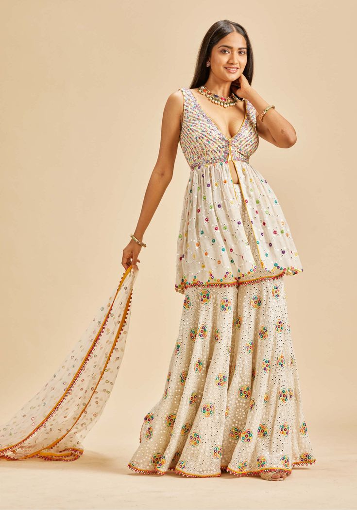 Editor's Note Off-white georgette garara and peplum top with net dupatta embroidered in multicoloured resham and patra Color: Off-white Fabric: Georgette and net Components: Garara, top and dupatta Occasion: Haldi mehndi Disclaimer: Product color may slightly vary due to photographic lighting sources or your monitor setting. Care: Dry Clean Only About the Designer Nitika Gujral’s journey with designing clothes started almost four decades back while she was still in high school and held her first Georgette Garara, Designing Clothes, Blouse Yoke, White Peplum Tops, White Peplum, Net Dupatta, How To Make Clothes, Photographic Lighting, White Fabric