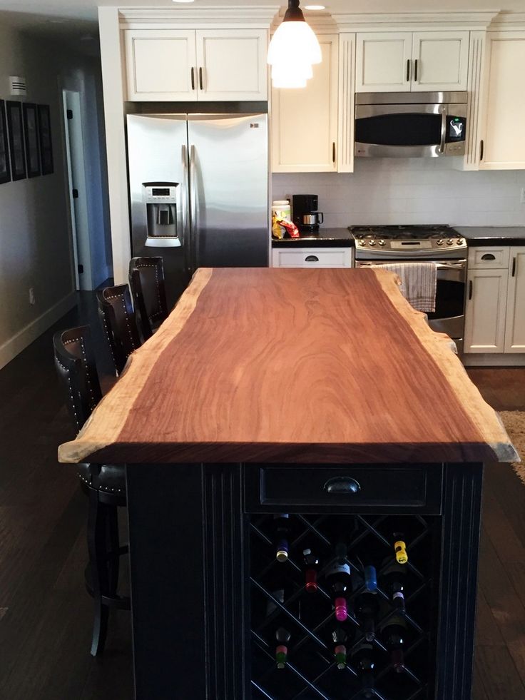 a kitchen with an island made out of wood in the center and white cabinets on both sides