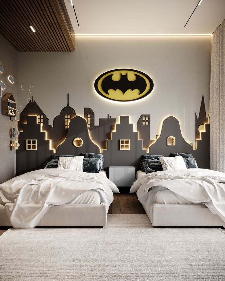 two beds in a bedroom with batman wall decals on the walls and lights above them